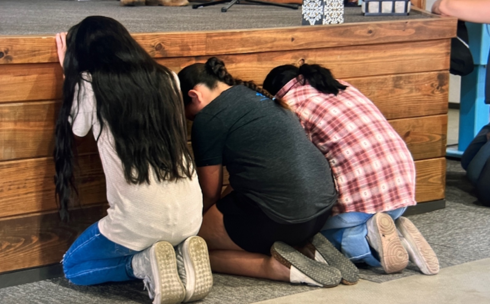 Girls from the home kneeling in prayer beside a wooden altar.